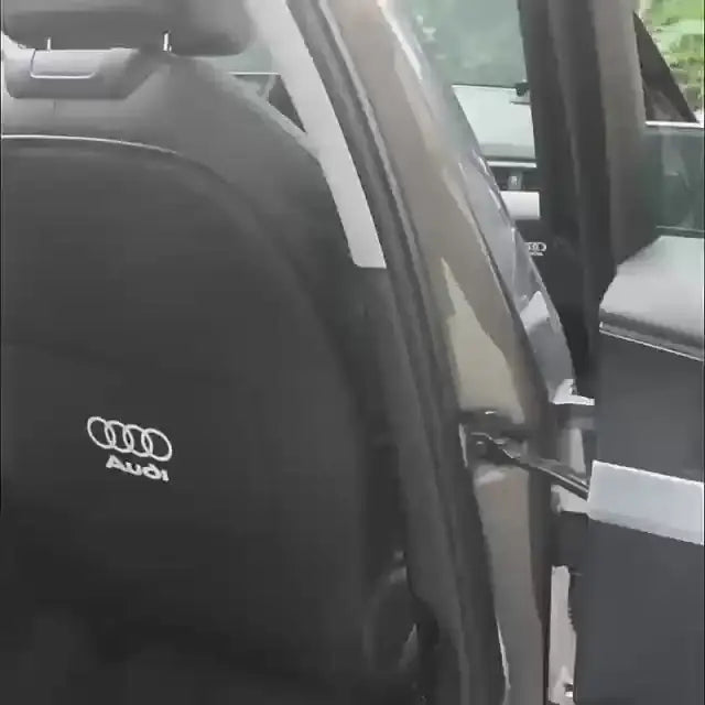 Audi car interior with black seat featuring Audi logo, door open, showing side mirror and window trim