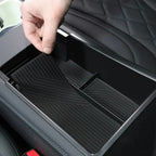 Black rubber car center console organizer mat with textured grip, fitting snugly in EV storage compartment