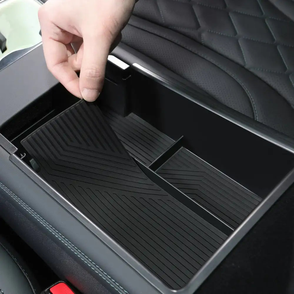Black rubber car center console organizer mat with textured grip, fitting snugly in EV storage compartment